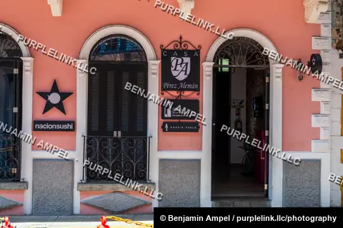 Casco Viejo, Panama City, Panama - August 2023: A row of pink and white colonial buildings with arched doorways and business signage lines a street in the historic quarter.