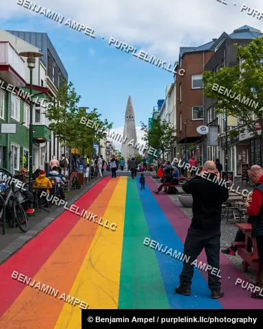 Reykjavik, Iceland - June 2024: A rainbow-painted pedestrian street lined with colorful shops leads toward Hallgrimskirkja church in the distance.
