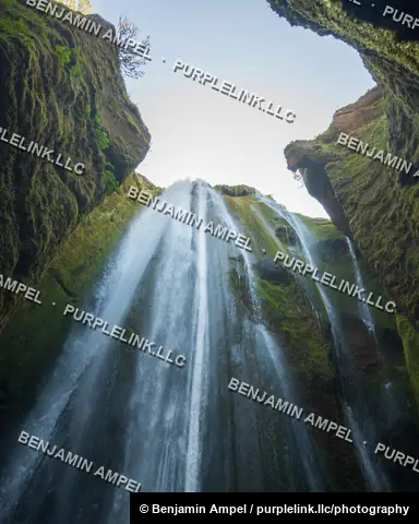 Gljúfrabúi waterfall plunges through a narrow, moss-lined canyon opening in south Iceland.