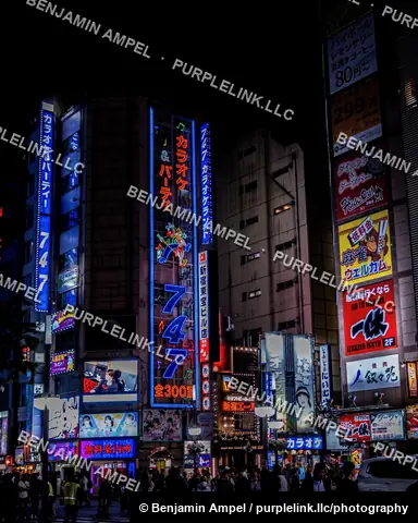 Tokyo, Japan - June 2025: Tall neon signs advertising karaoke and entertainment venues illuminate a Kabukicho building facade after dark.