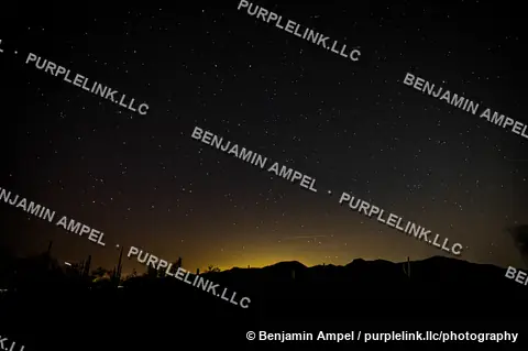 A dense field of stars fills the night sky above a silhouetted mountain ridge in the Sonoran Desert, Arizona.