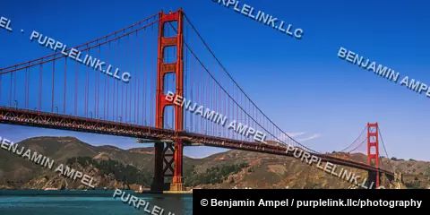 The north tower of the Golden Gate Bridge rises above San Francisco Bay under a clear blue sky.