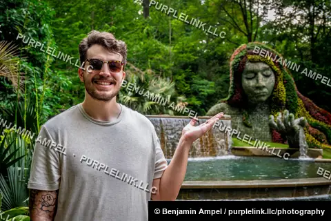 Atlanta, Georgia - May 2026: A visitor gestures toward the Earth Goddess topiary sculpture at the Atlanta Botanical Garden.