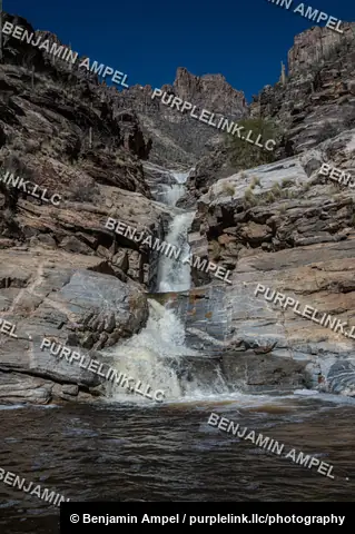 Water cascades over layered rock into a still pool at the base of a Sonoran Desert waterfall.