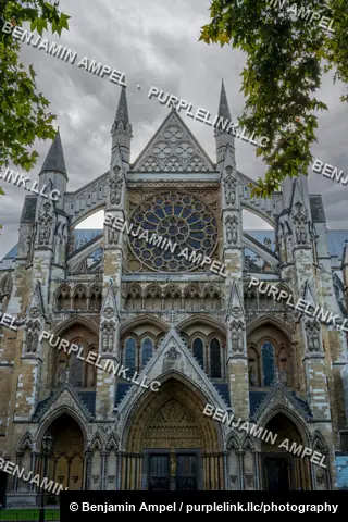 London, England - October 2025: The elaborate rose window and Gothic spires of Westminster Abbey's north transept rise above autumn trees.