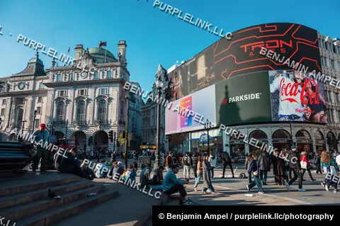 London, England - October 2025: Large digital advertising screens light up the curved facade above shops and crowds at Piccadilly Circus.