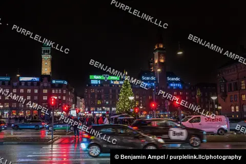 Copenhagen, Denmark - December 2025: Traffic light trails and a lit Christmas tree fill Radhuspladsen (City Hall Square) at night, framed by illuminated brand signage and historic towers.