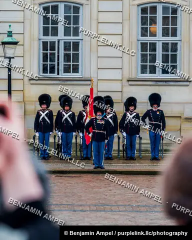Copenhagen, Denmark - December 2025: Members of the Danish Royal Life Guards in bearskin hats stand at attention outside Amalienborg Palace as onlookers photograph them.
