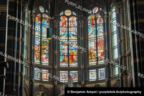 Amsterdam, Netherlands - June 2026: Detailed stained glass windows depict religious scenes above the altar of the Basilica of Saint Nicholas.