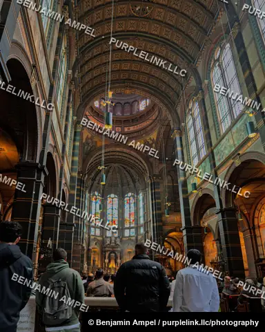 Amsterdam, Netherlands - June 2026: Visitors gather inside the domed interior of the Basilica of Saint Nicholas beneath painted arches.
