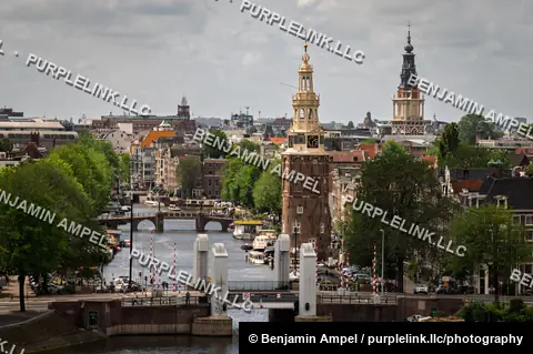 The historic Montelbaanstoren tower rises above a canal drawbridge lined with brick buildings in Amsterdam.