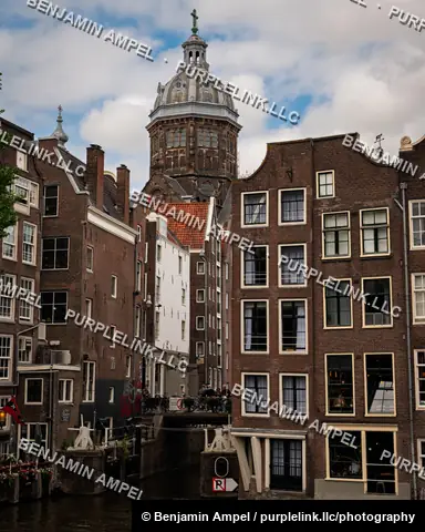 Amsterdam, Netherlands - June 2026: Traditional canal houses lean together beneath the dome of the Basilica of Saint Nicholas.