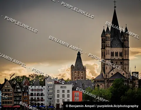 Cologne, Germany - June 2026: Gothic cathedral towers rise above the Rhein Hotel and pastel gabled buildings of the old town at dusk.
