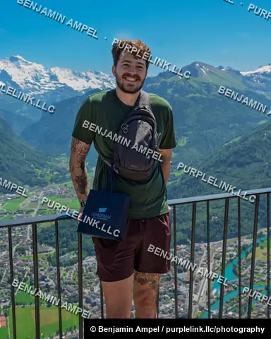 Jungfraujoch, Switzerland - June 2026: A smiling visitor holds a Top of Europe gift bag with snow-covered alpine peaks in the background.
