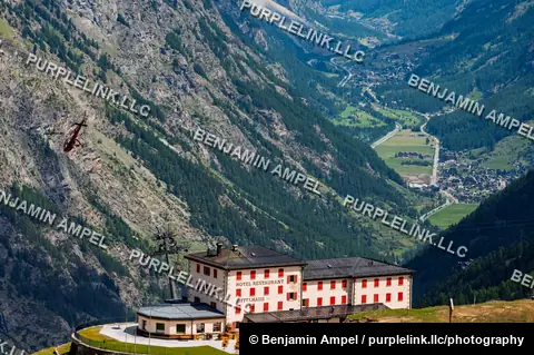 Zermatt, Switzerland - June 2026: A helicopter flies past the Riffelhaus Hotel perched on a mountainside above the Zermatt valley.