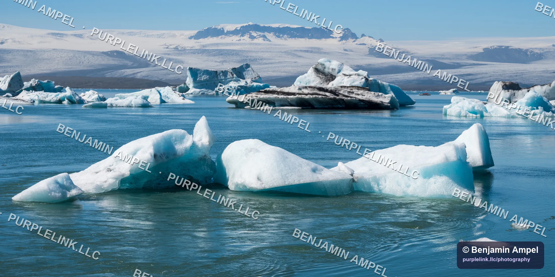Blue and white icebergs floating on Jökulsárlón lagoon with a glacier beyond